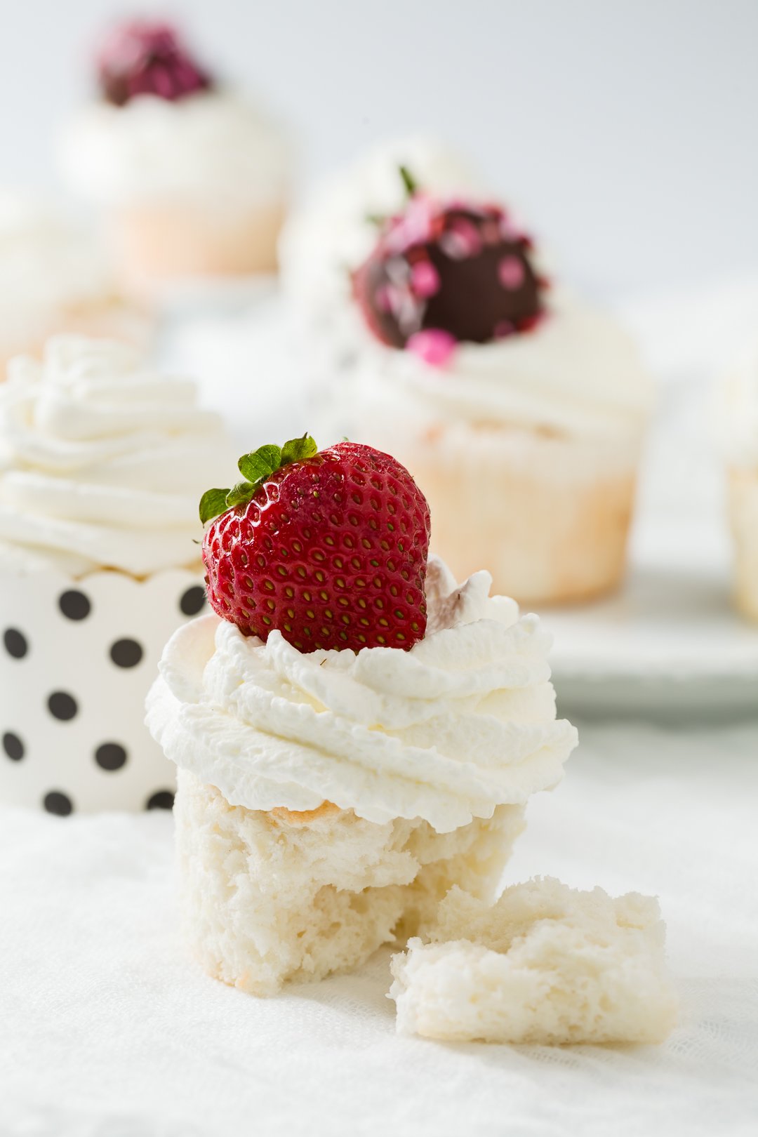 a grouping of angel food cupcakes topped with strawberries