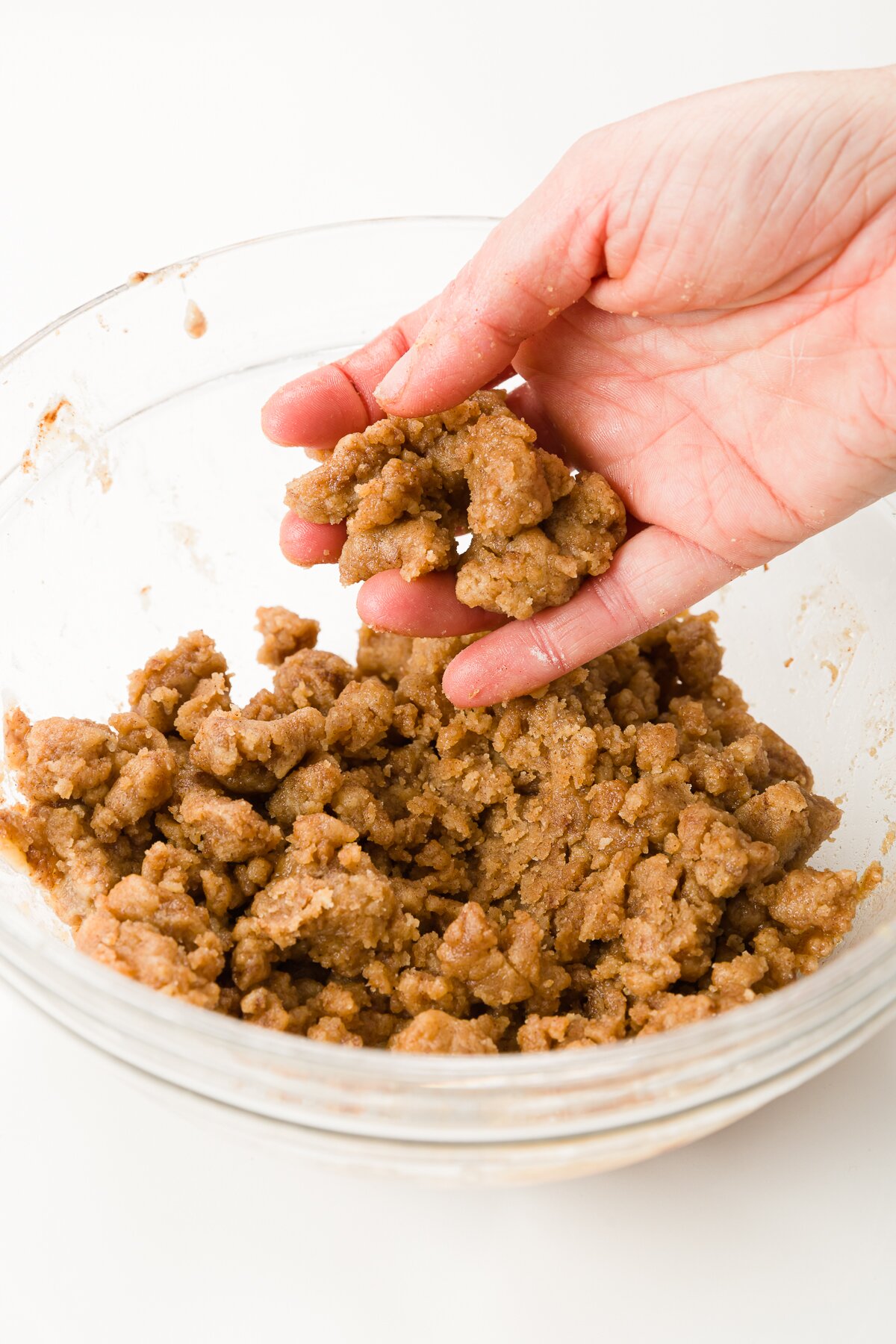 Mixing crumbs by hand in a glass bowl