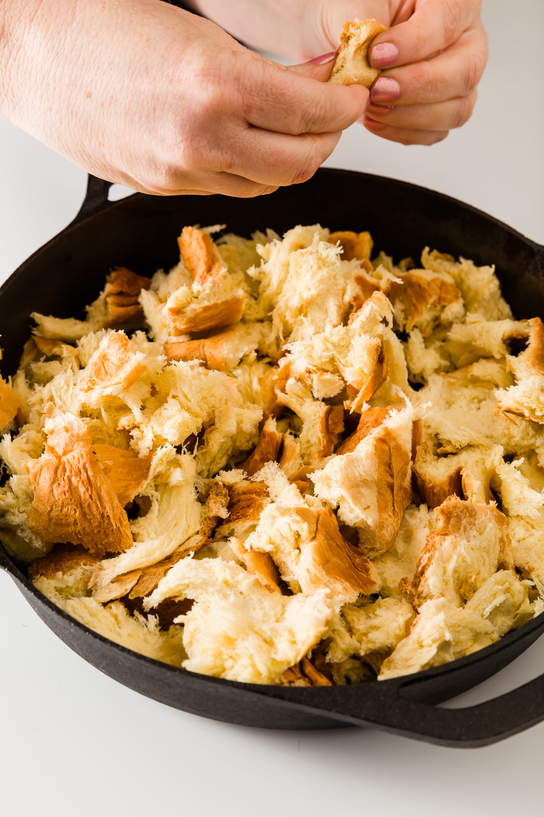 Ripping brioche bread into a skillet