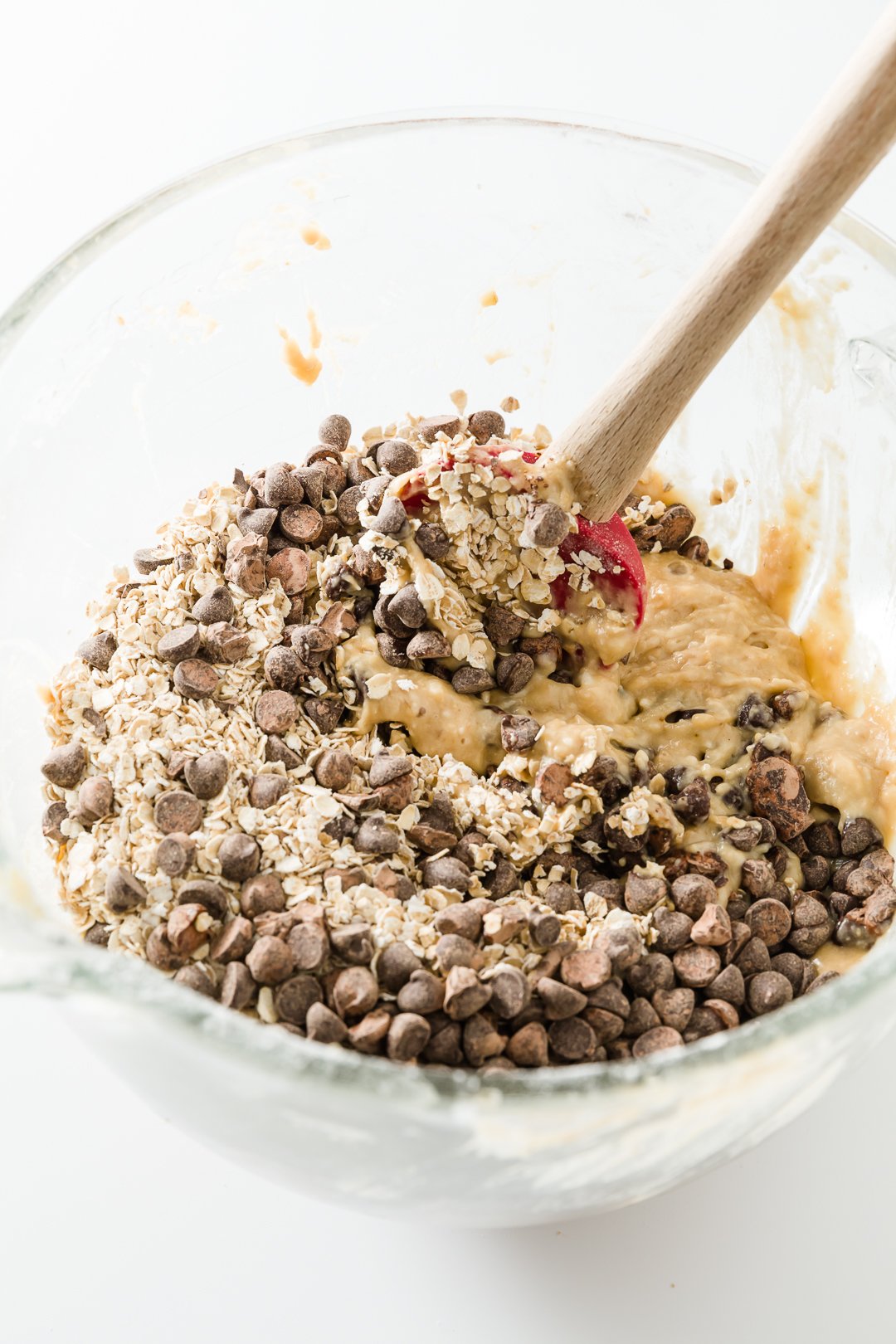 Stirring oats and chocolate chips into banana muffin batter