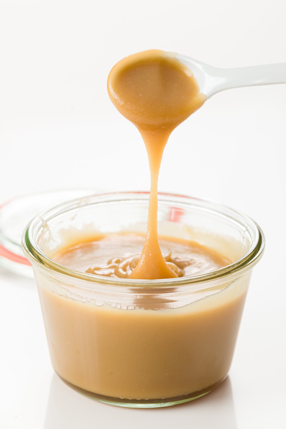 Butterscotch sauce dripping from a spoon into a jar