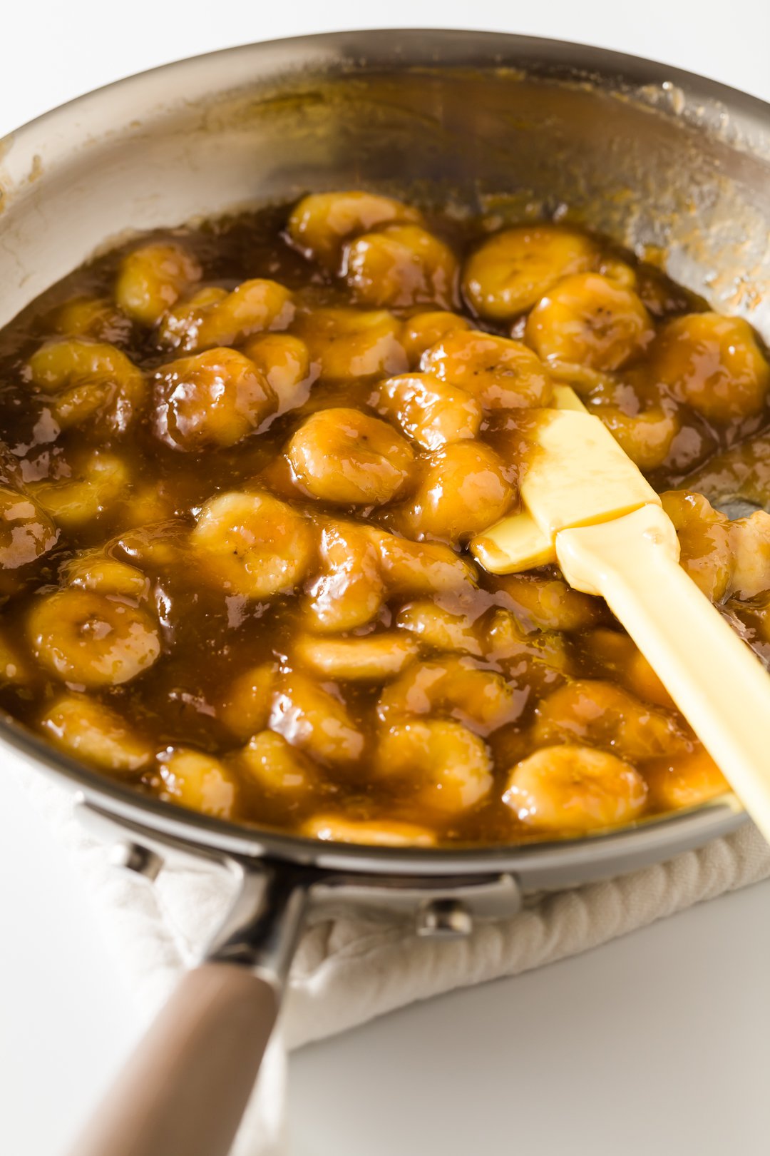 a skillet of caramelized bananas with a spatula