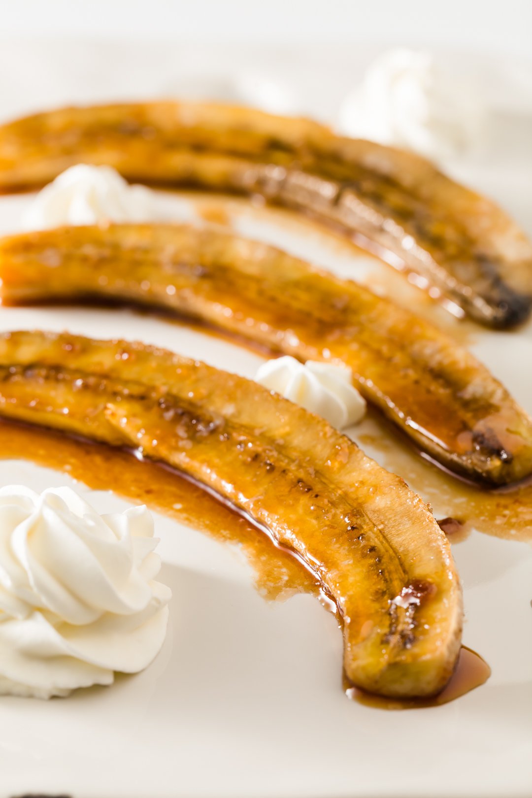 caramelized banana halves on a plate with whipped cream