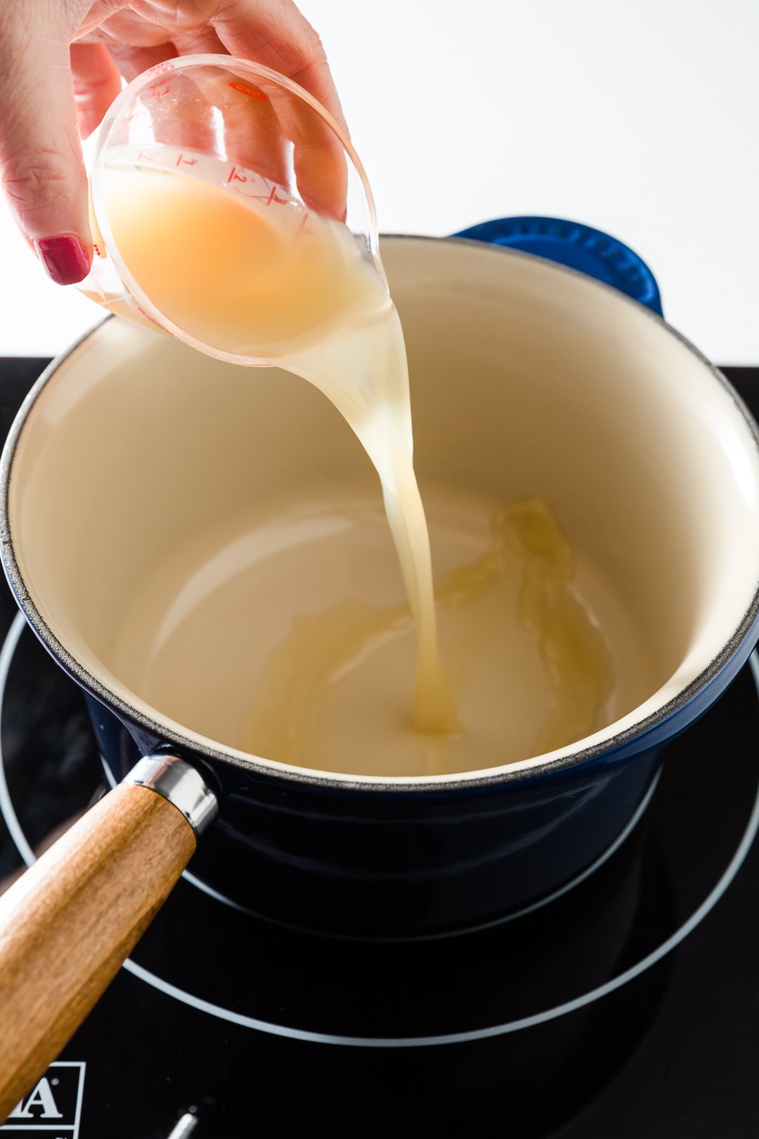 Pouring lemon juice into a pot on the stove.