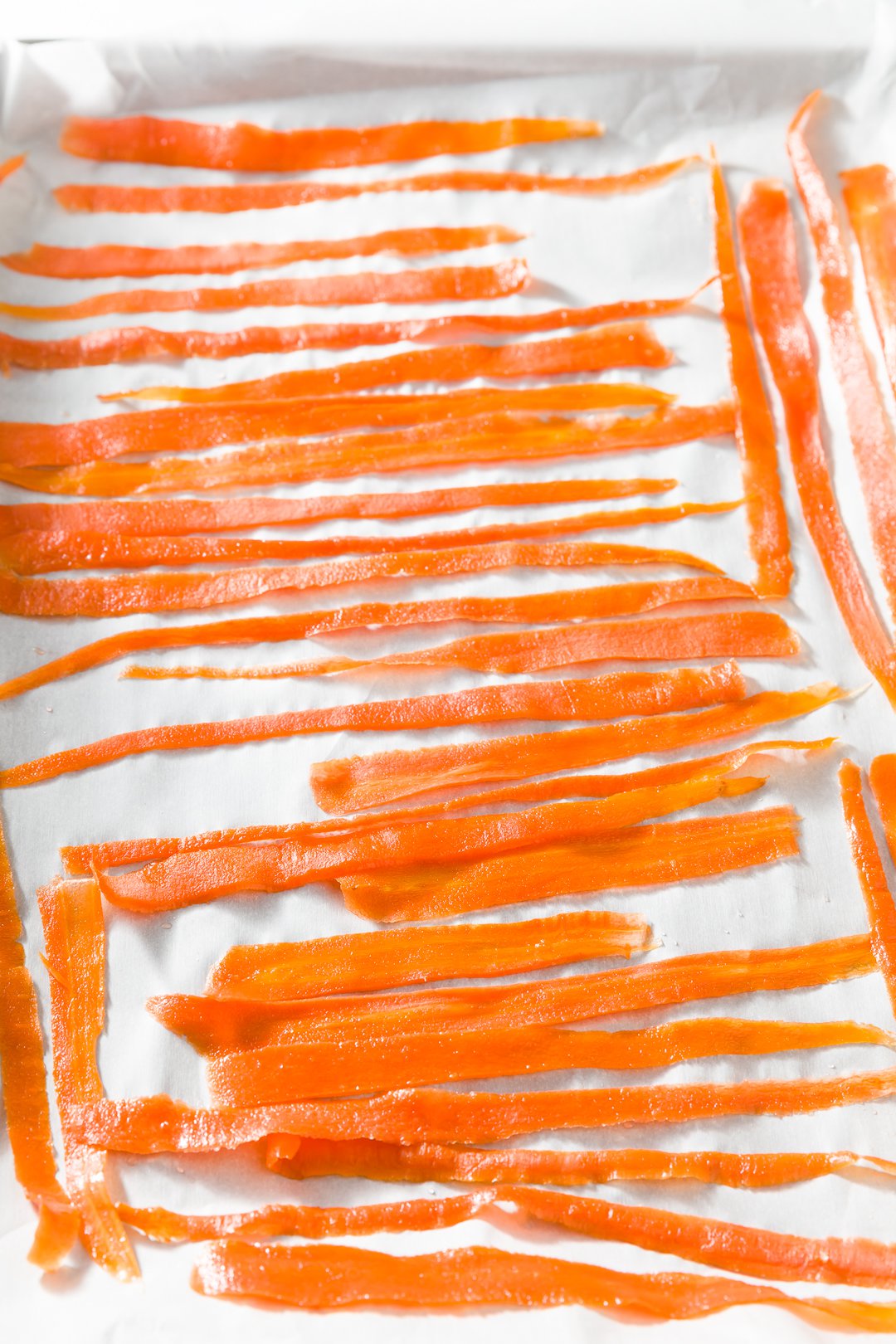 Carrot curls laid out flat on a baking sheet lined with parchment.