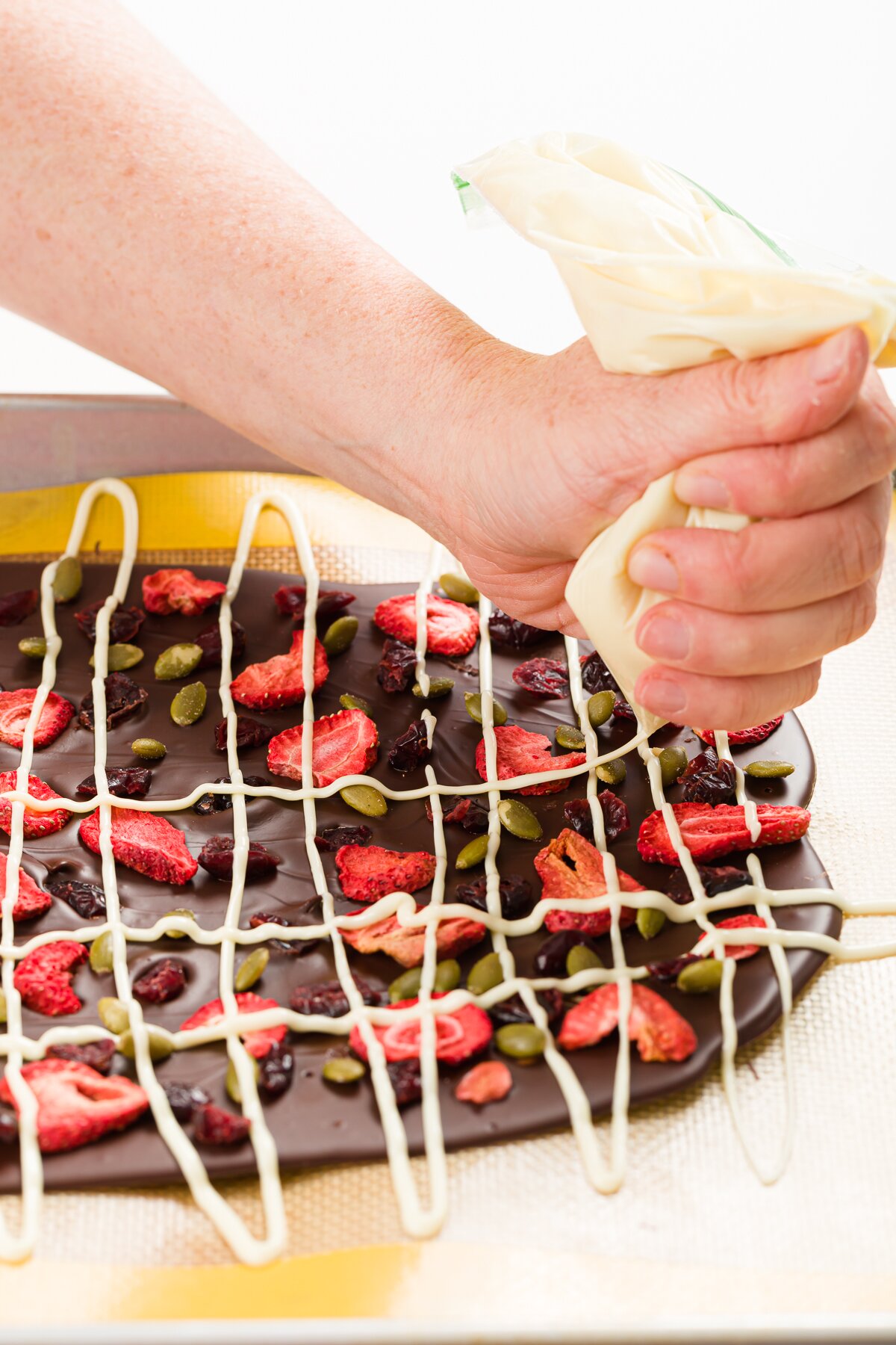 Piping white chocolate onto chocolate bark