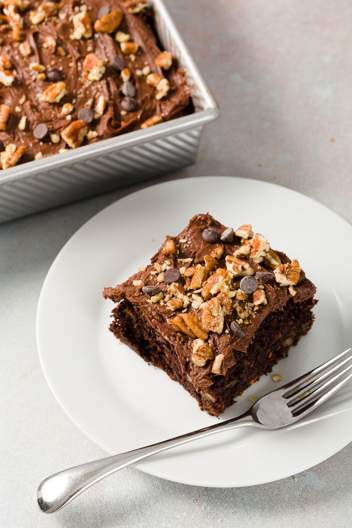 Top down shop of a slice of chocolate carrot cake on a white plate with a fork