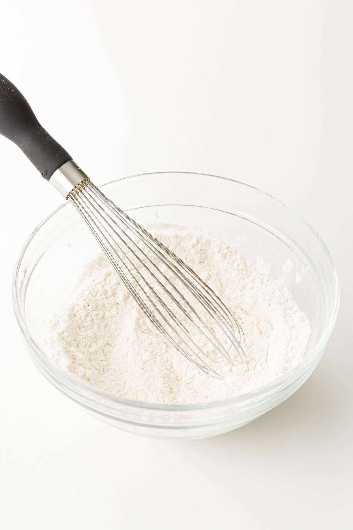 Whisking dry ingredients in a glass bowl.