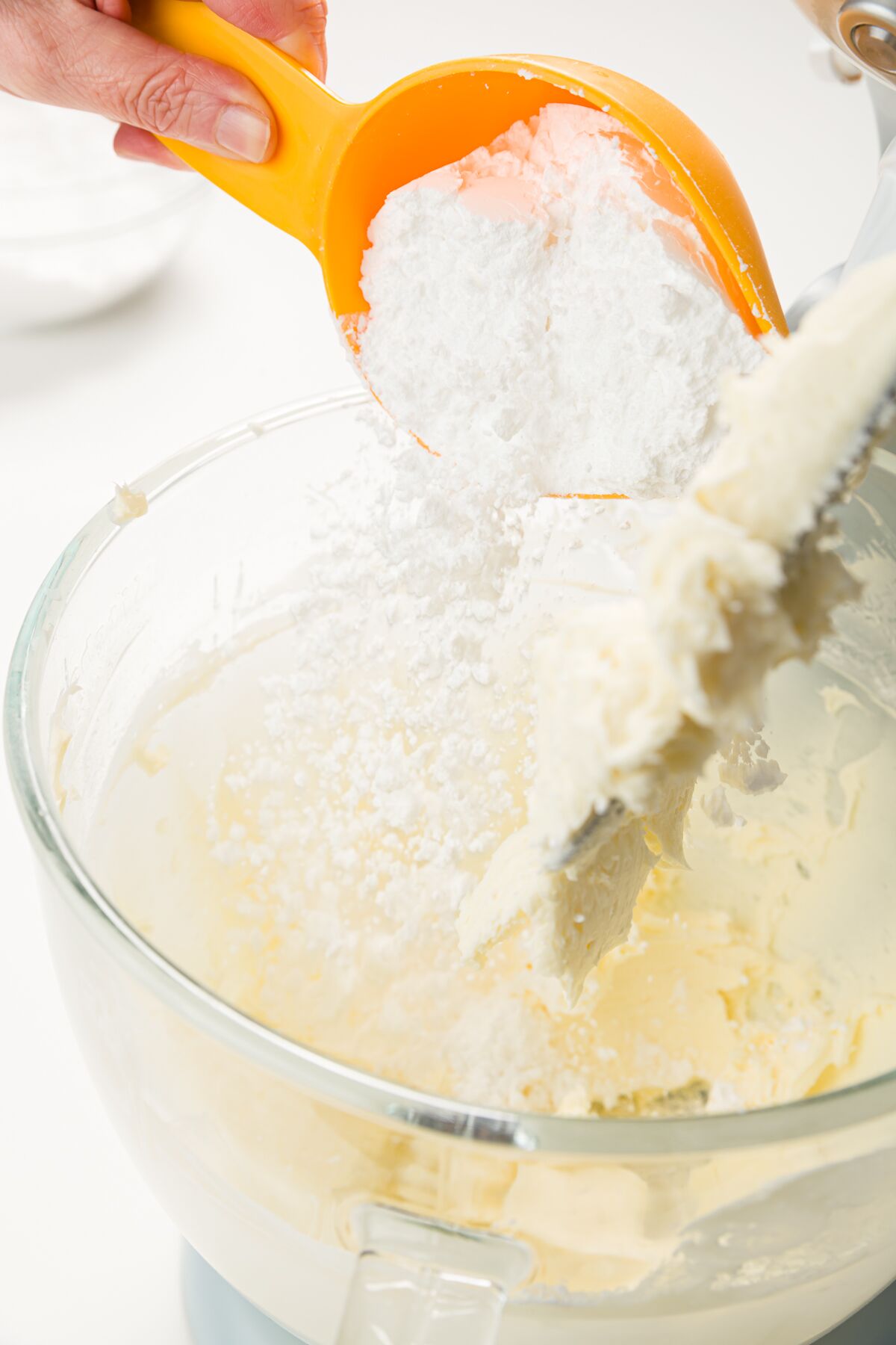 Adding powdered sugar to mixing bowl with whipped butter