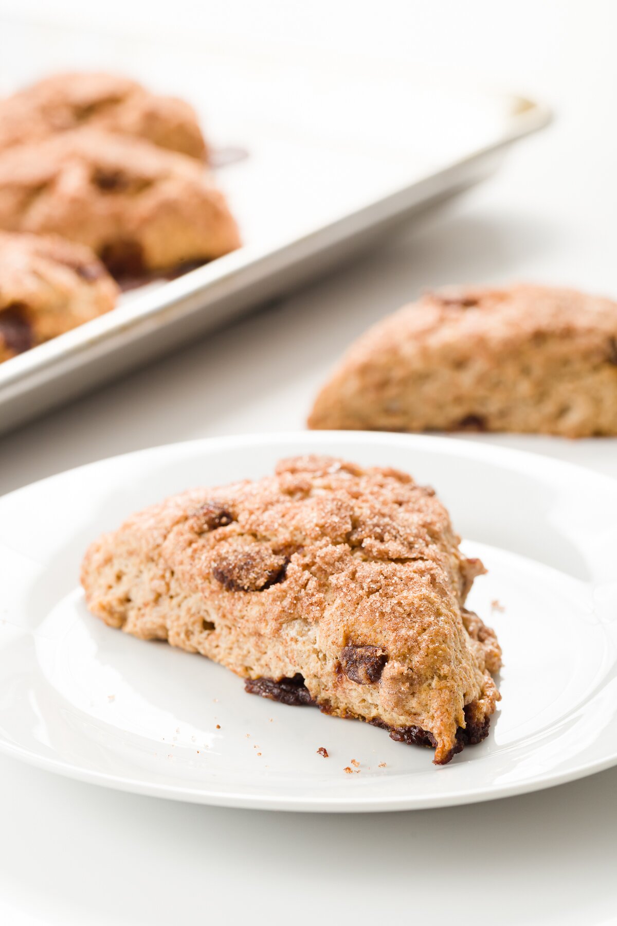Cinnamon scone on a white plate with scones in the background