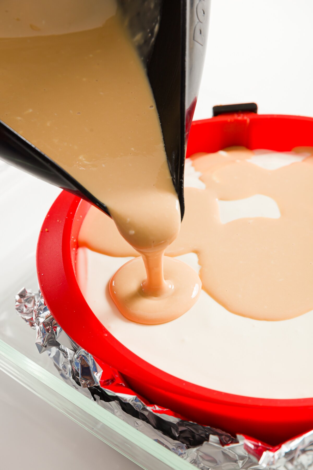 Pouring dulce de leche layer onto cheesecake