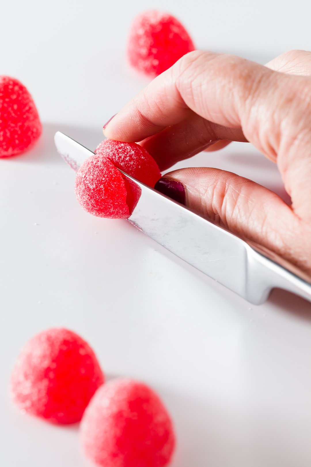 Cutting red gumdrops in half with a knife