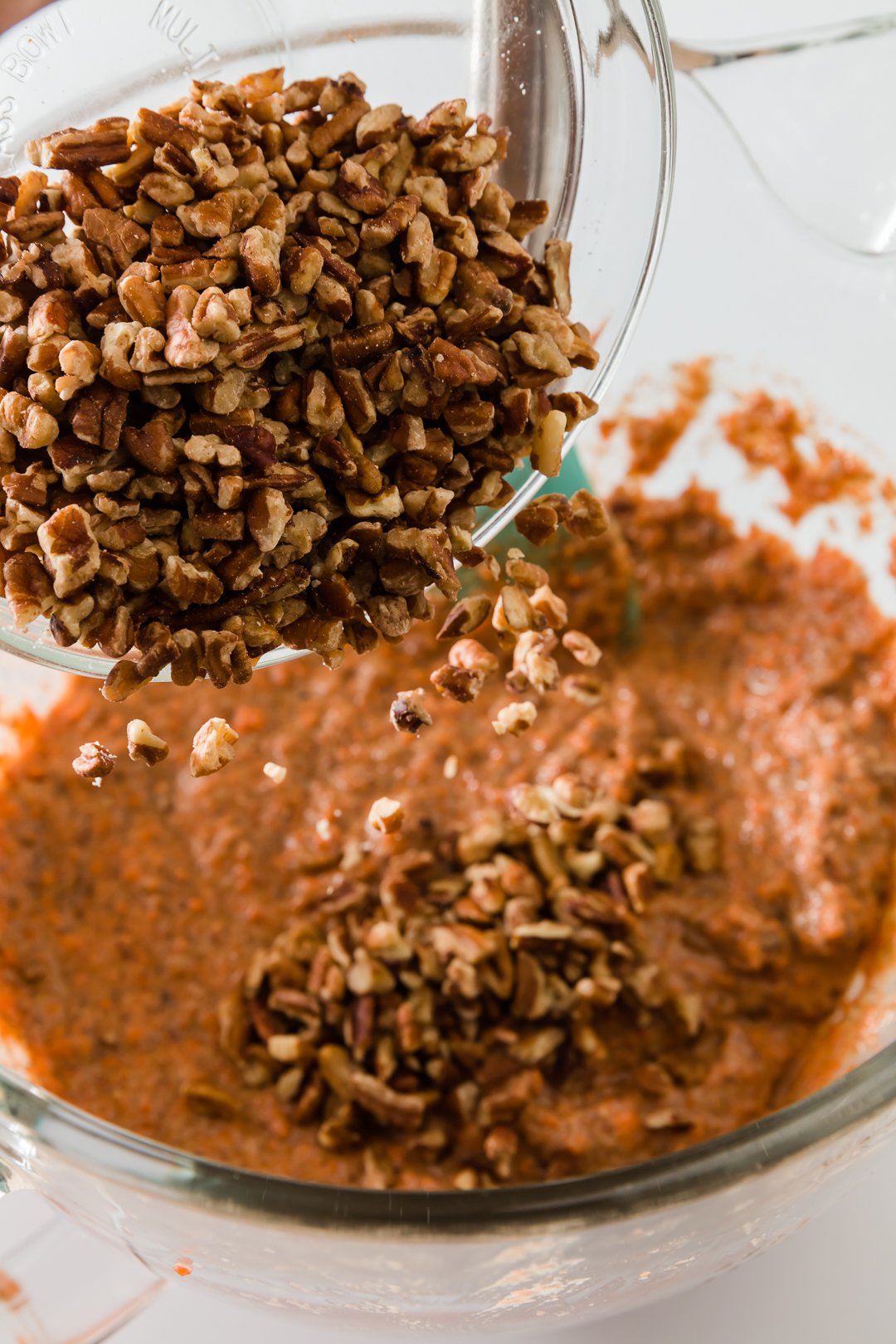 Folding chopped pecans into carrot cake