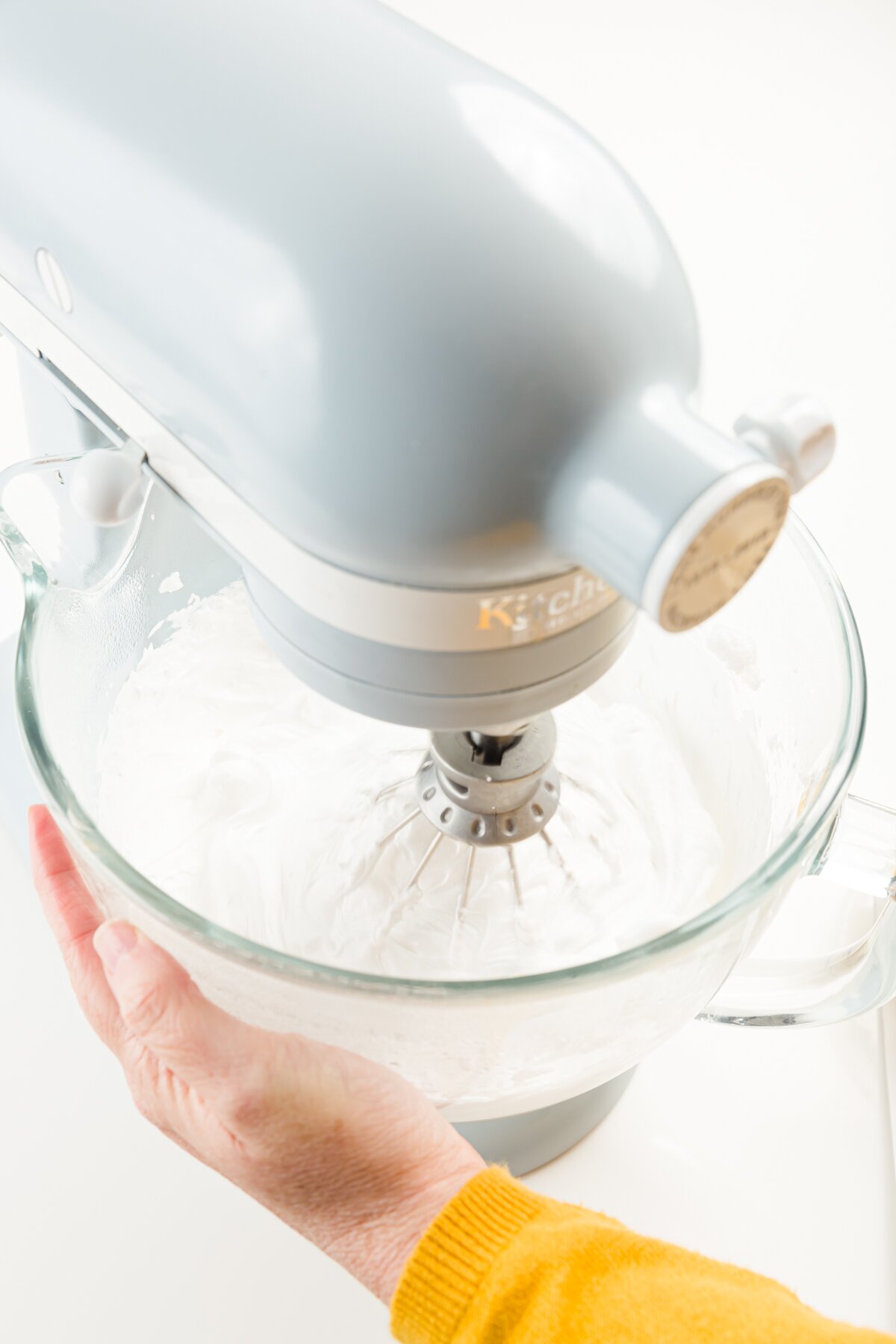 tight shot of Stef holding a mixer bowl to test the temperature of Italian meringue buttercream frosting