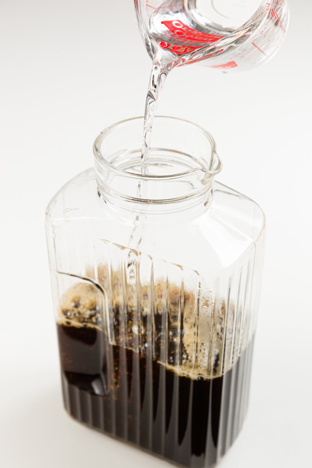 adding vodka to sweetened coffee in a jug to make homemade Kahlua