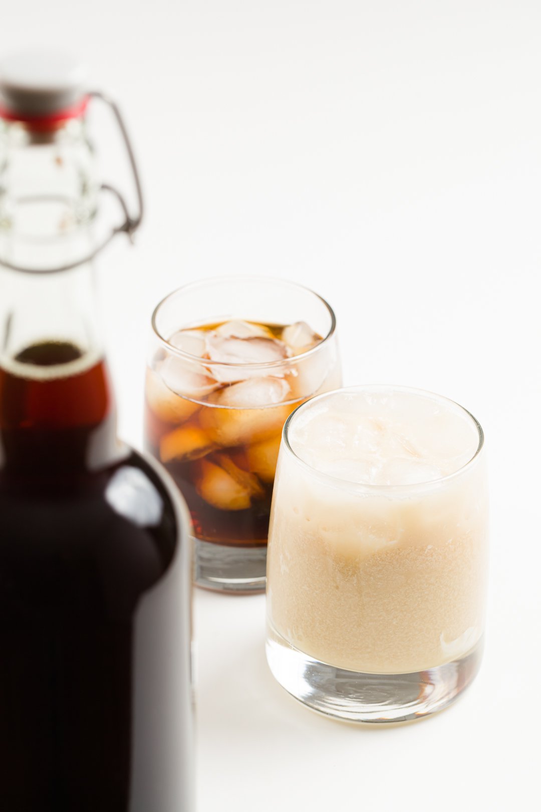two cocktails made with homemade Kahlua and a bottle of homemade Kahlua in the foreground