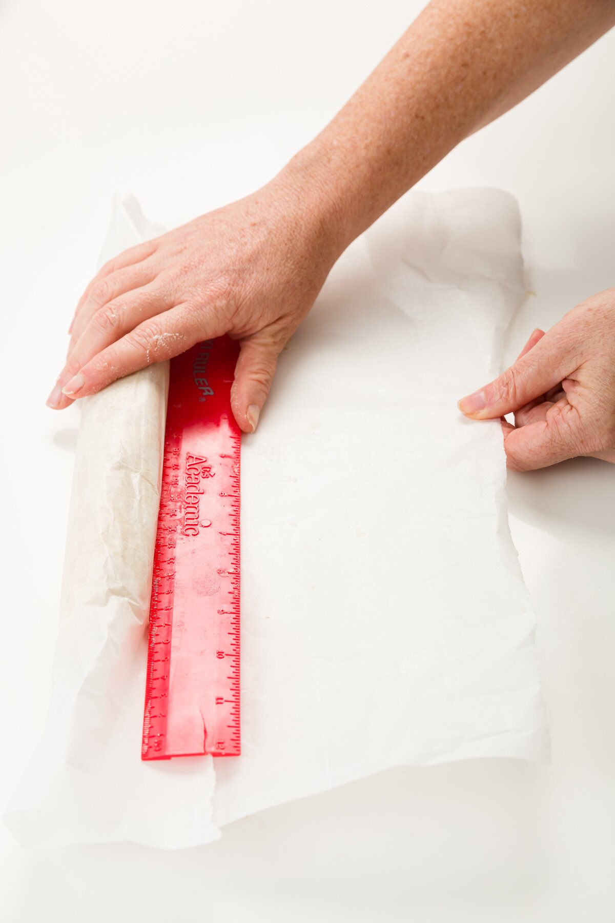 parchment log with a red ruler pressed up against it and hands pulling out the bottom of the parchment