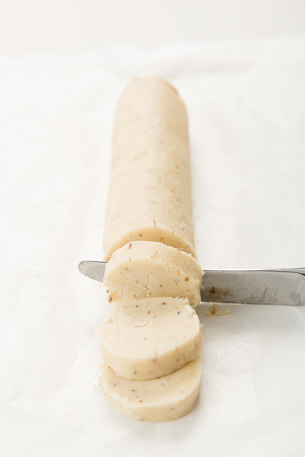 Knife cutting a slice off of a dough log