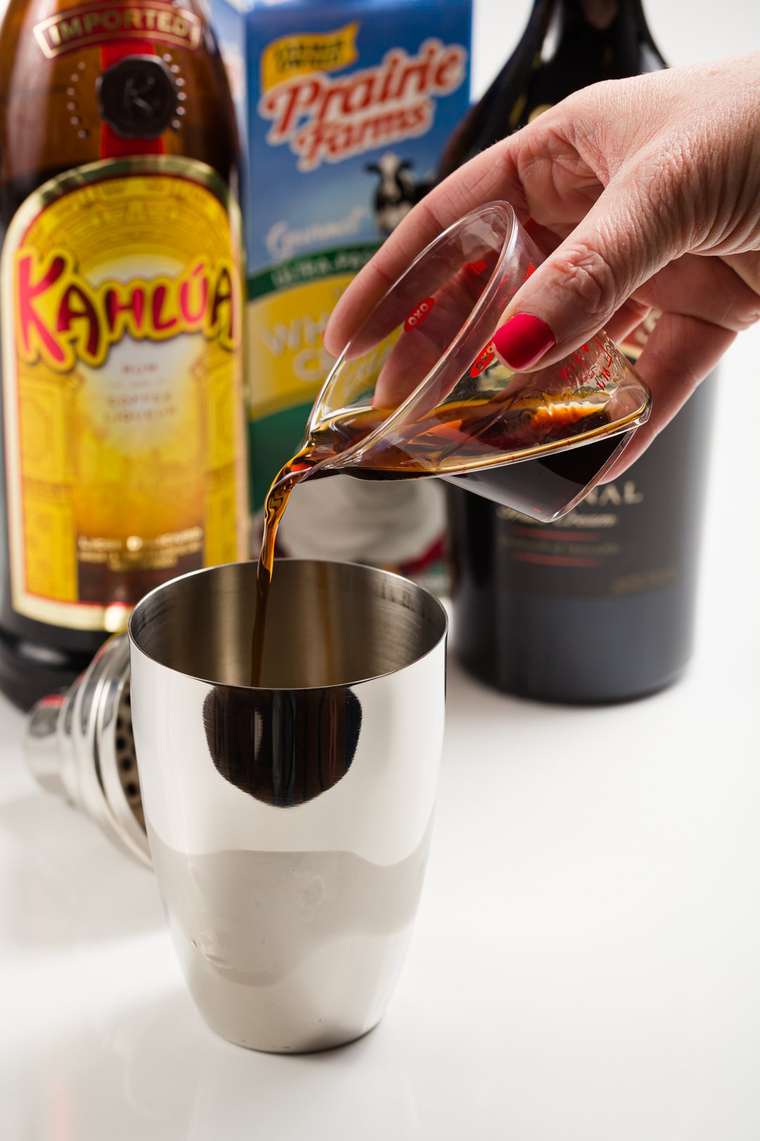 Kahlua added to a cocktail shaker with ice to make a mudslide cocktail