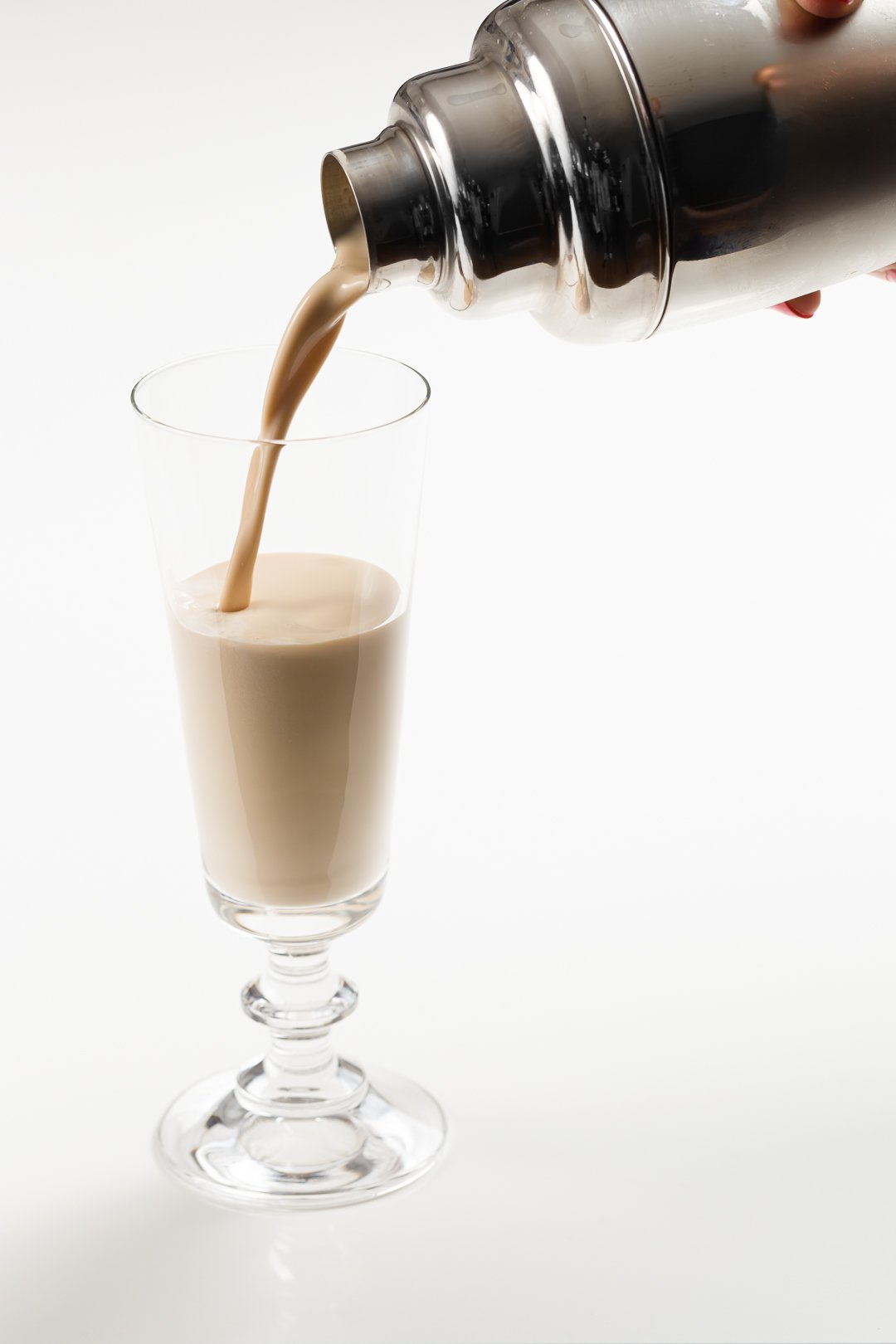 mudslide cocktail being poured from a cocktail shaker into a glass
