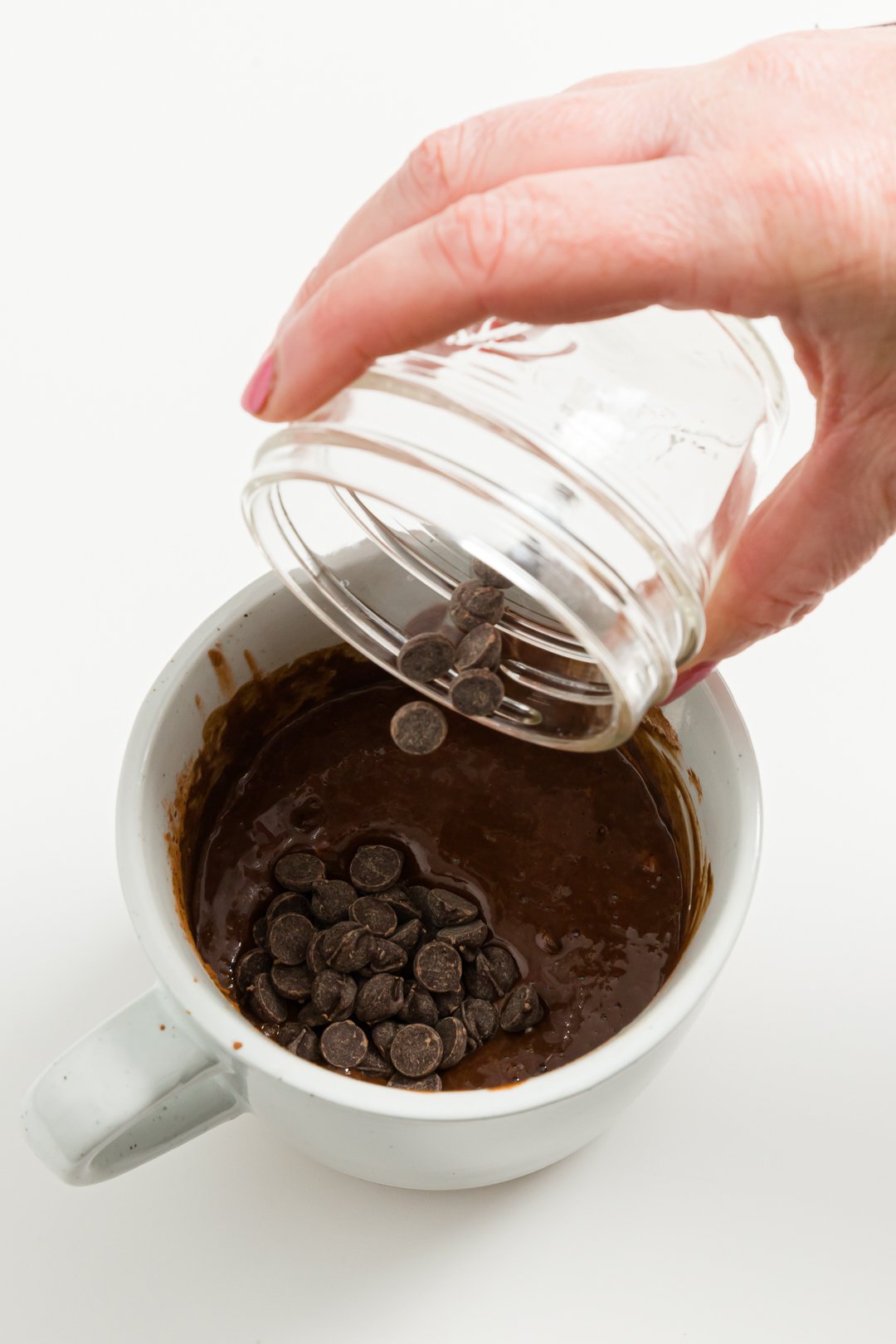 Adding chocolate chips to mug
