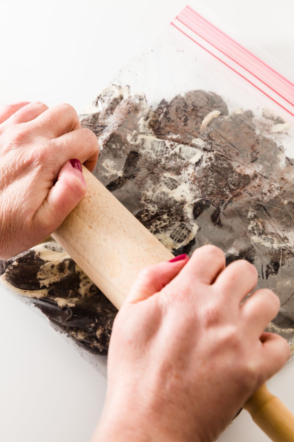 Rolling a rolling pin over a ZipLock bag filled with Oreos