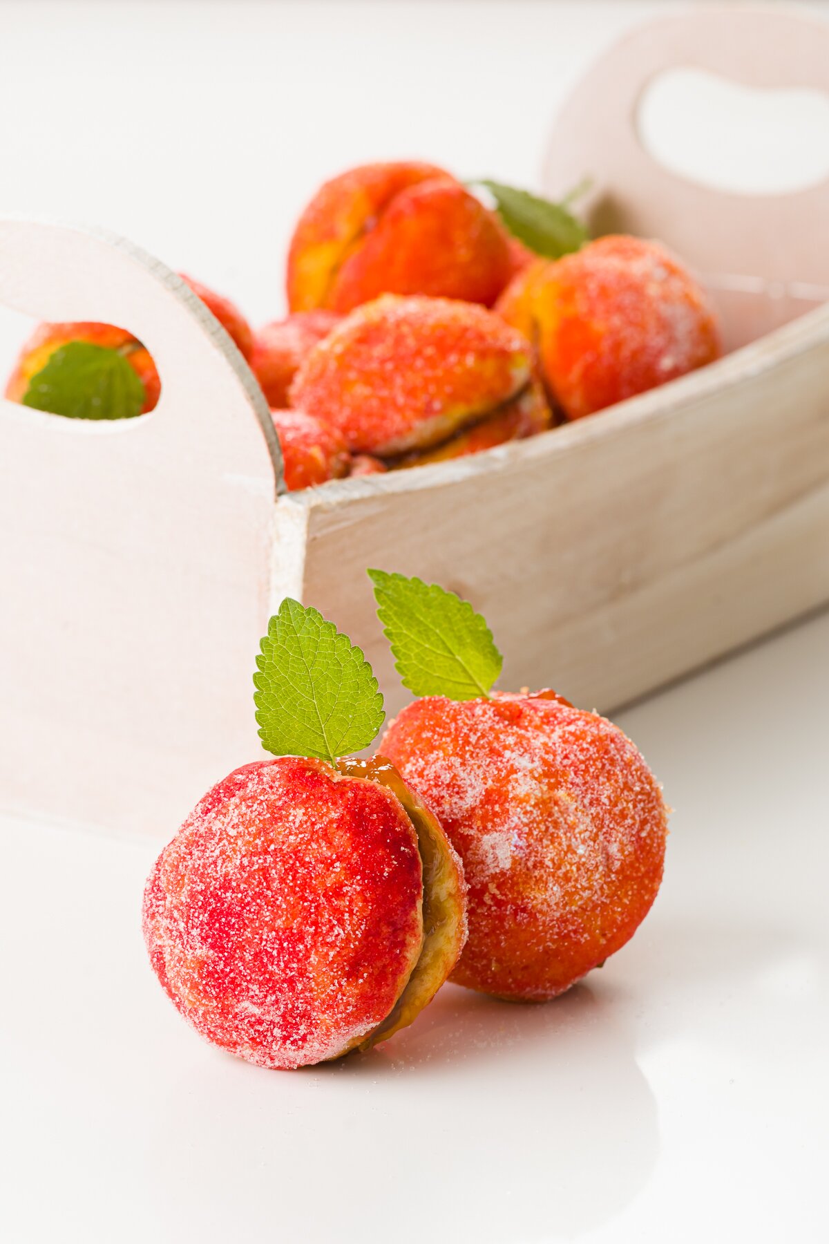 Two peach cookies in the foreground with a basket of cookies in the background