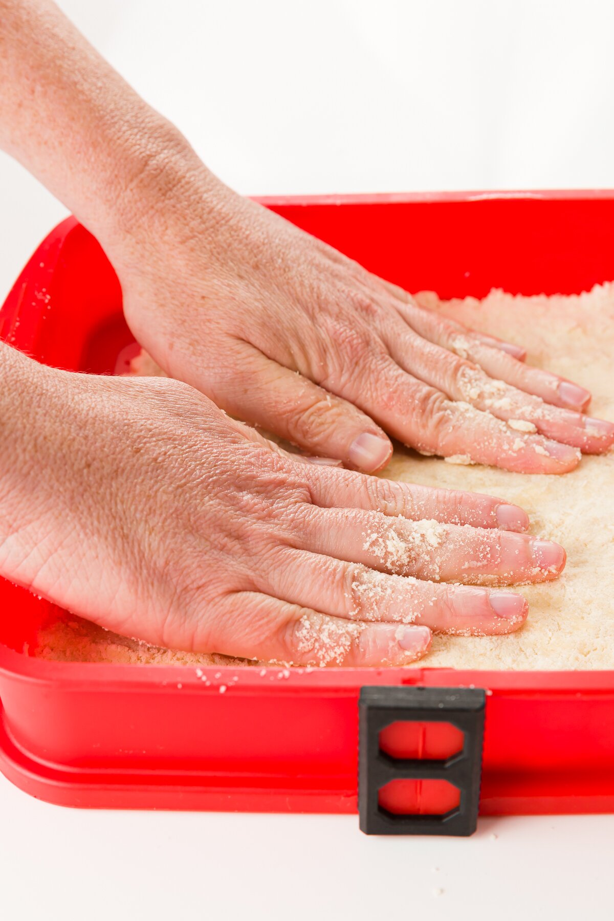 Pressing crust into a red baking pan