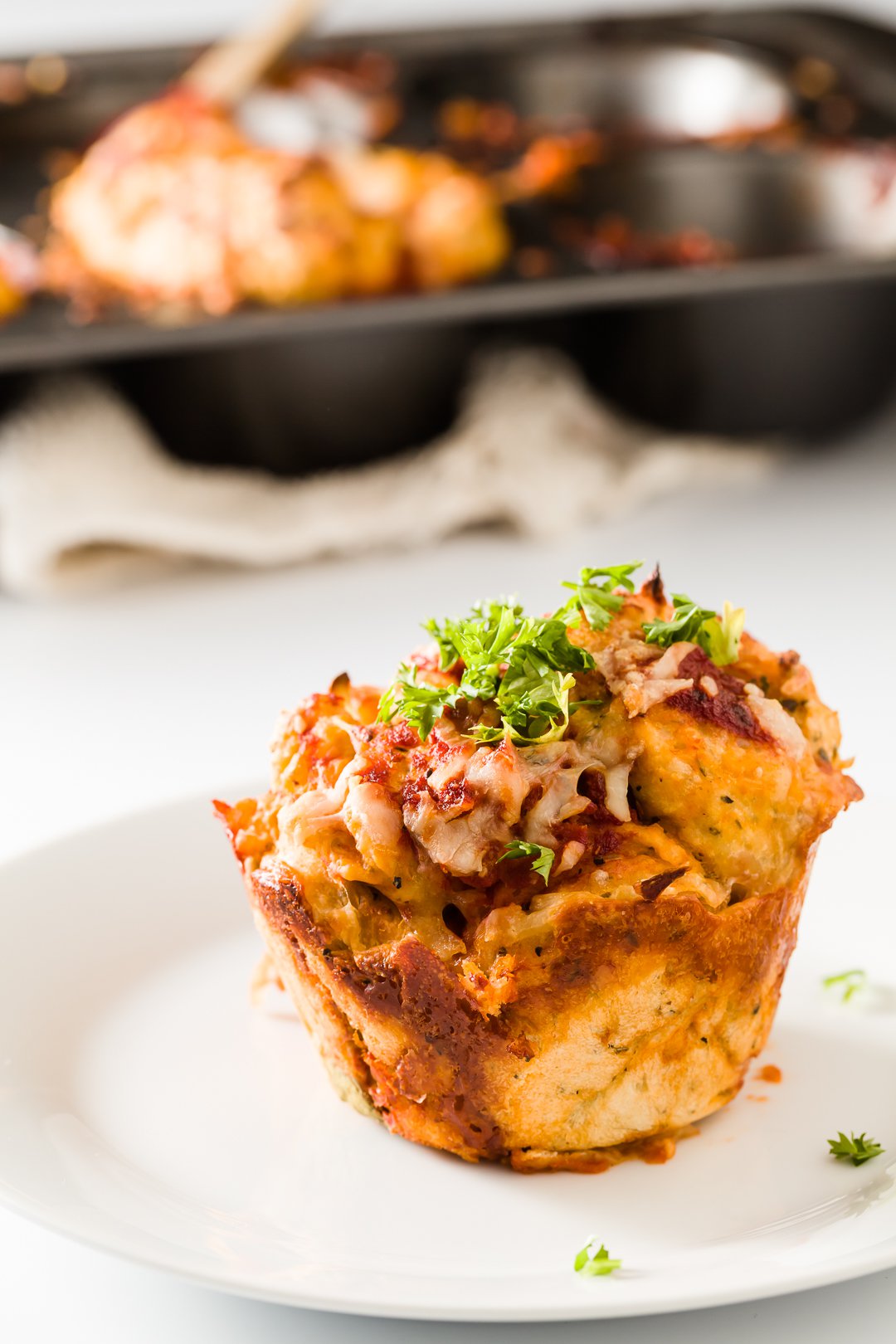 Pizza muffin with muffin tin behind it