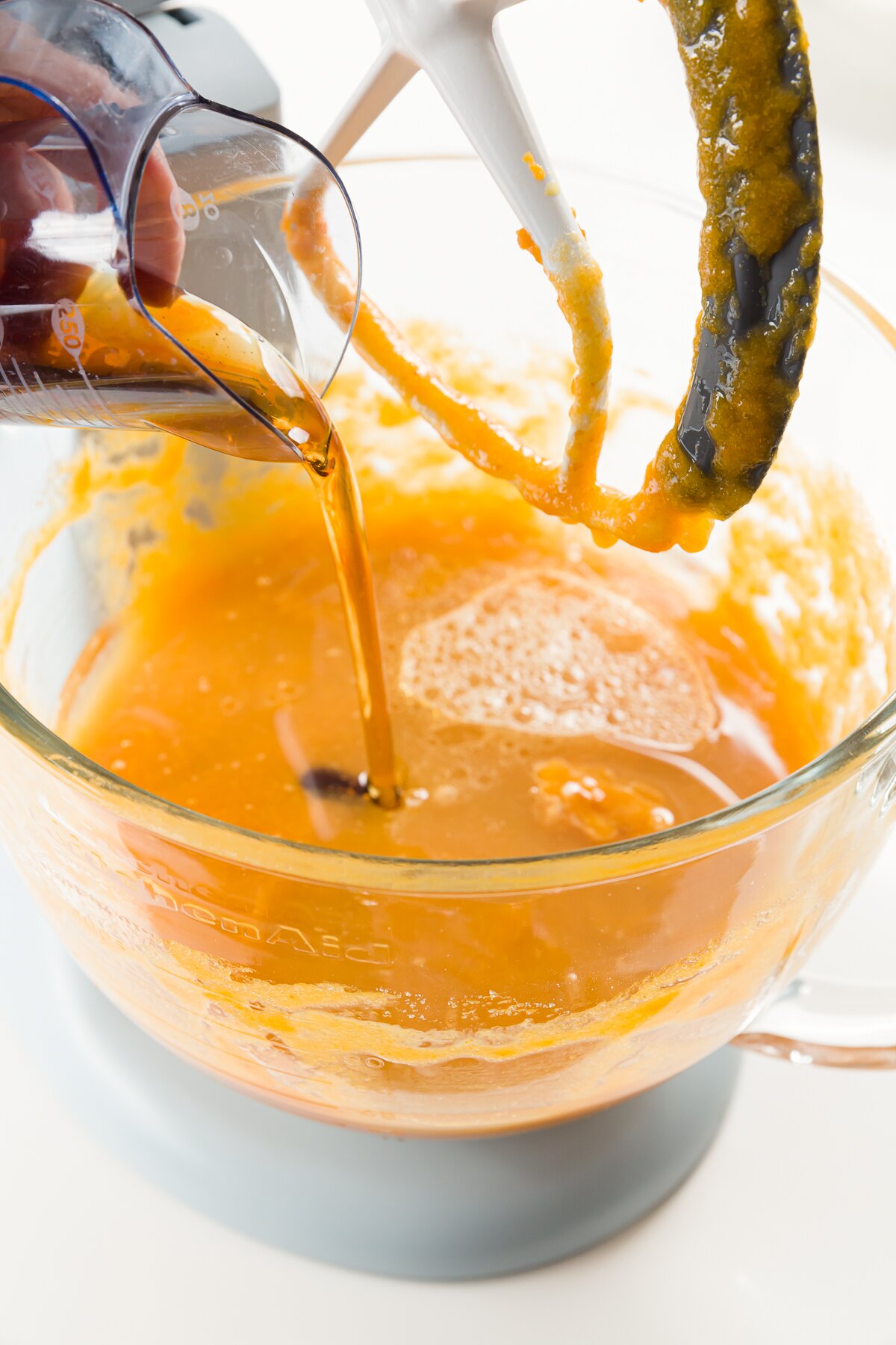 Adding maple syrup to kitchen aid mixer with pumpkin cupcake batter in it