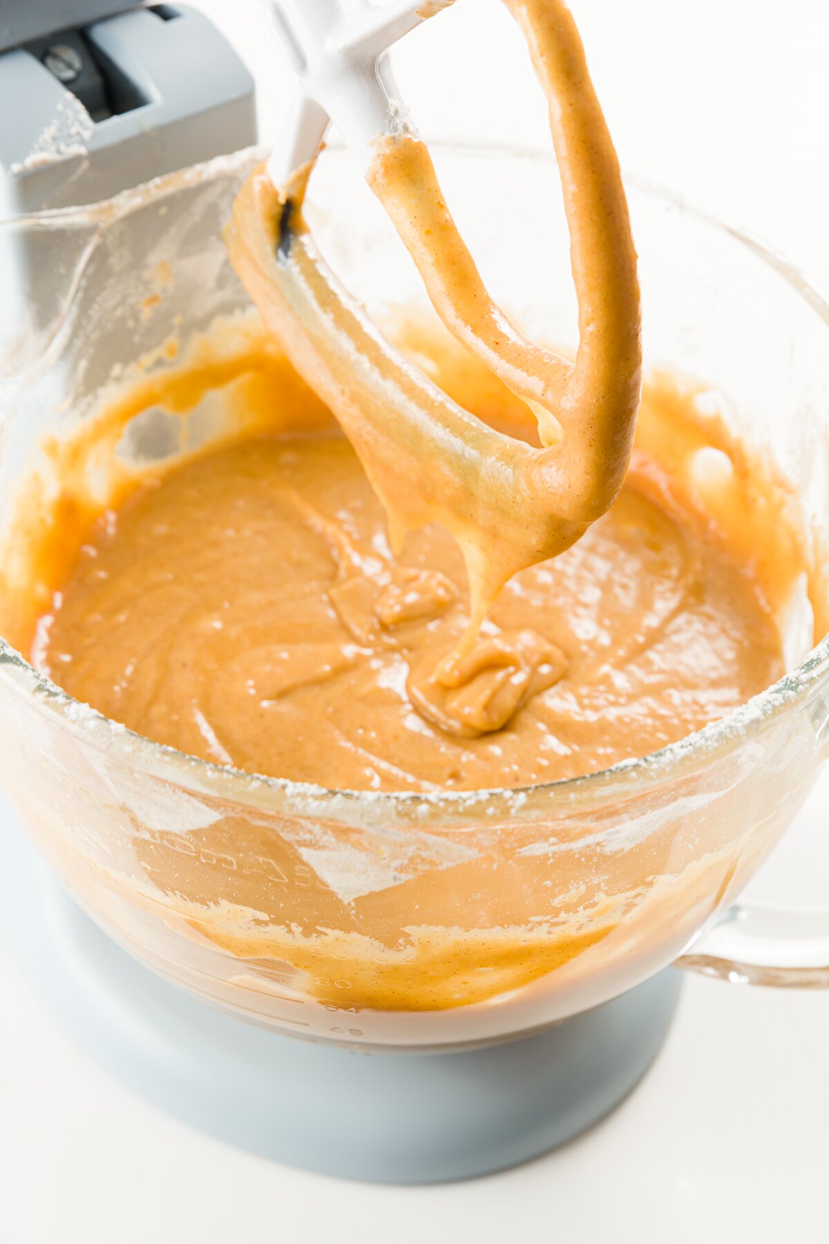 Pumpkin cupcake batter in a kitchenaid mixer with the beater raised. 