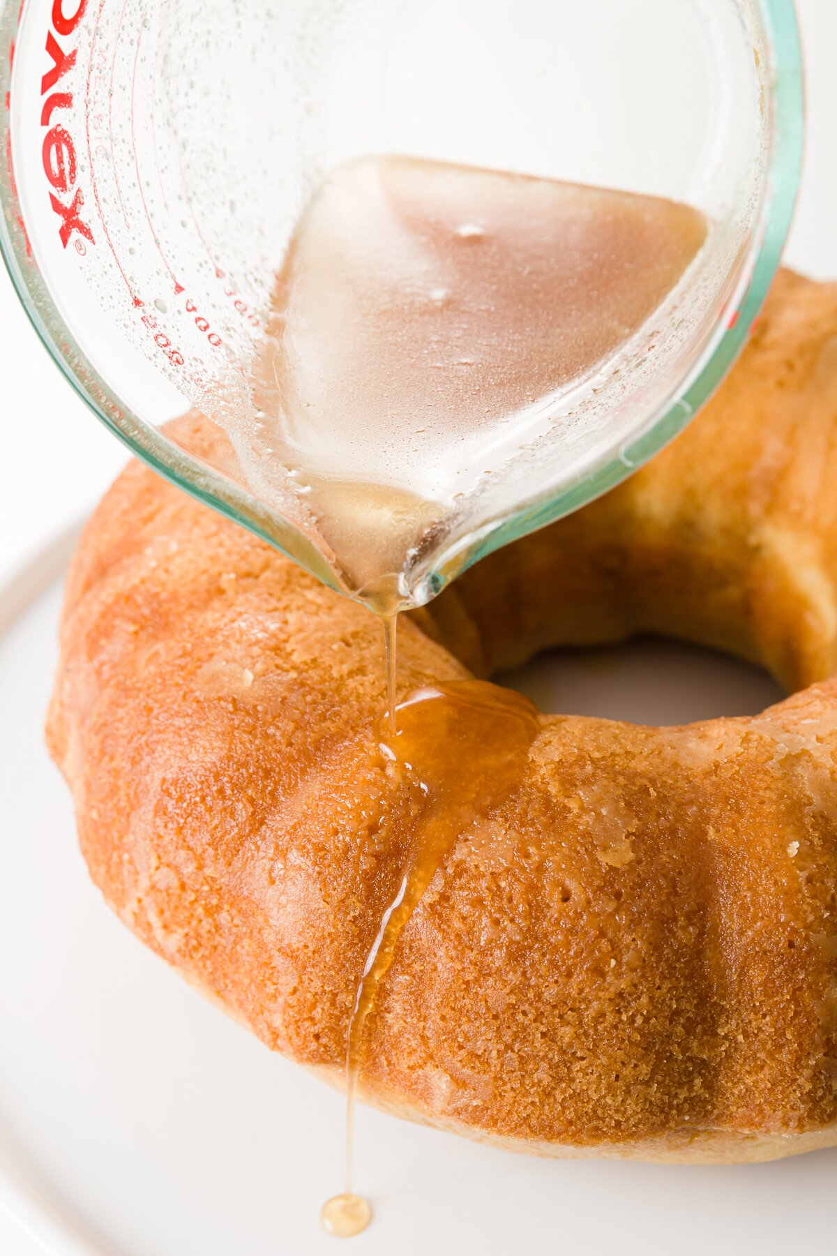 tight shot of Stef pouring rum syrup over the top of the cake