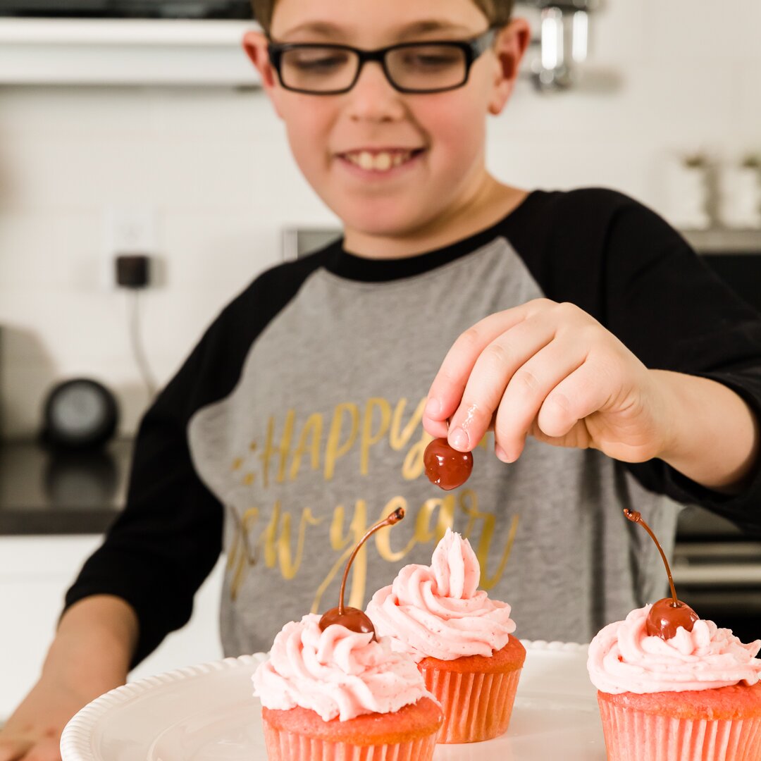 Myles adding a cherry to a cupcake