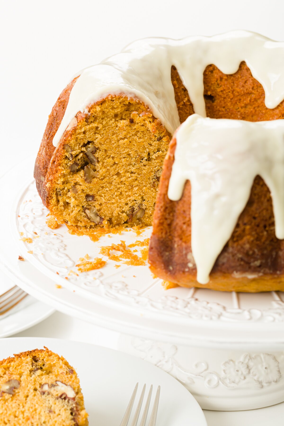Sweet potato Bundt cake on cake stand with a slice on a plate in front of it