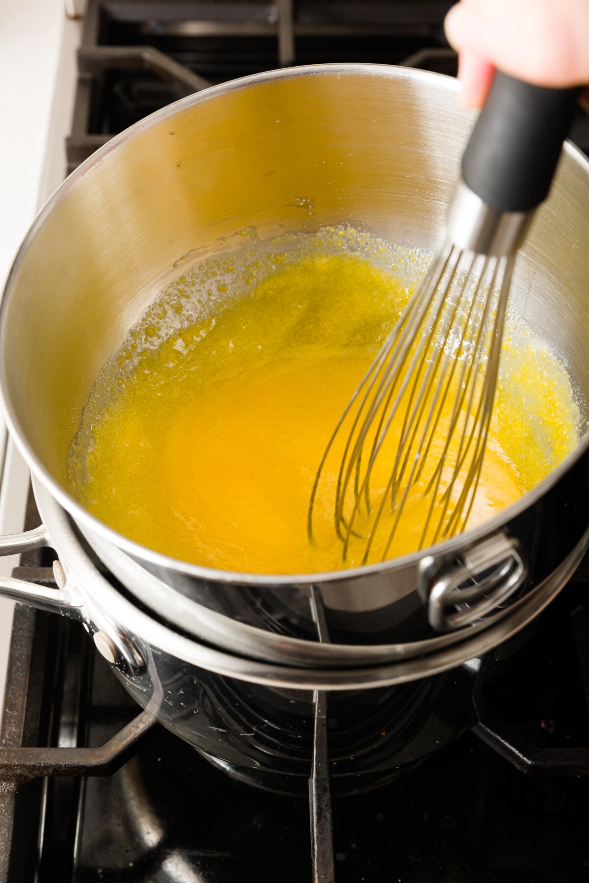 Stef whisking egg yolks and sugar in a bowl using a double boiler