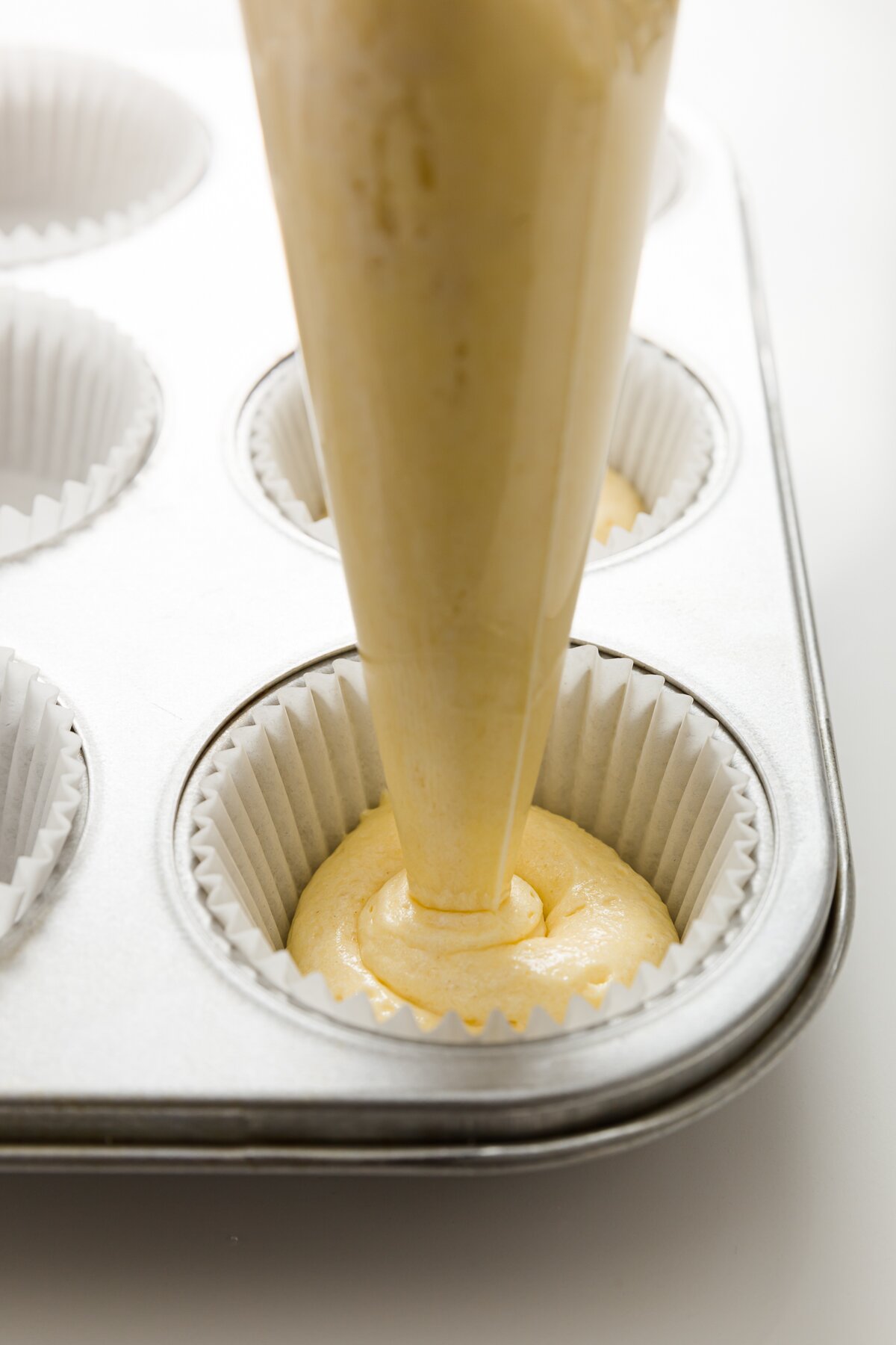 tight shot of Stef piping tiramisu cupcake batter into cupcake liners