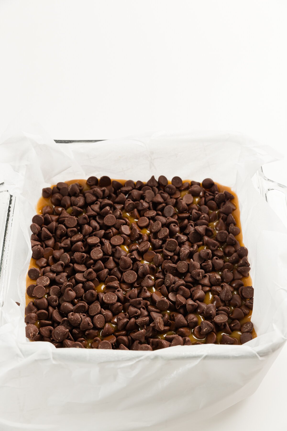 Top down of square dish filled with chocolate chips over toffee